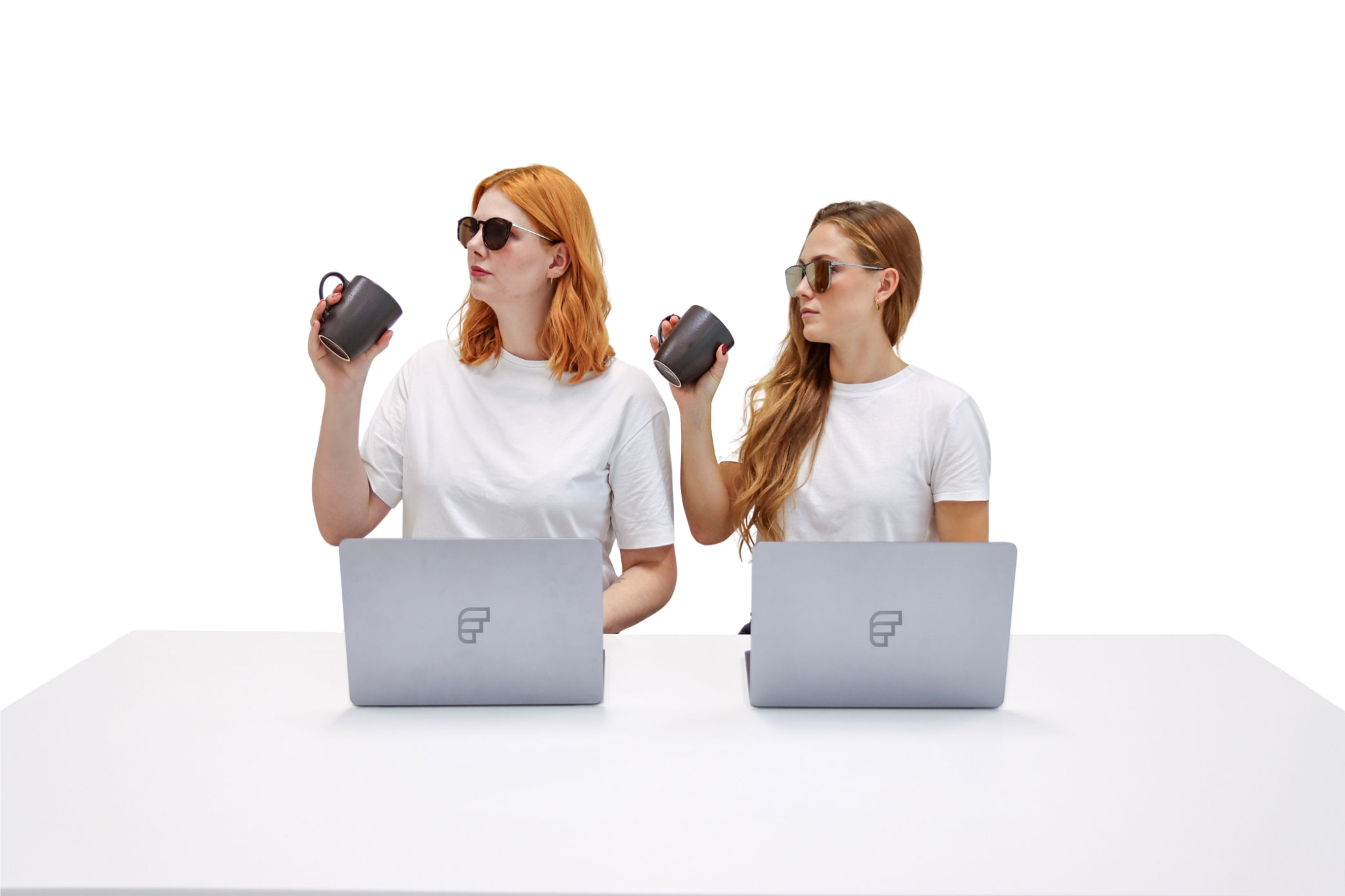 Bild von zwei Personen die an einem Computer arbeiten und dabei mit einer Kaffeetasse in der Hand in die selbe Richtung schauen